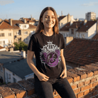 Тениска Лошия Лилав Мечок - тяло с усмивка на фона на градска панорама.